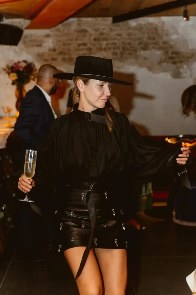 A woman in a black skirt and hat is dancing at a party near Harrods in Knightsbridge.
