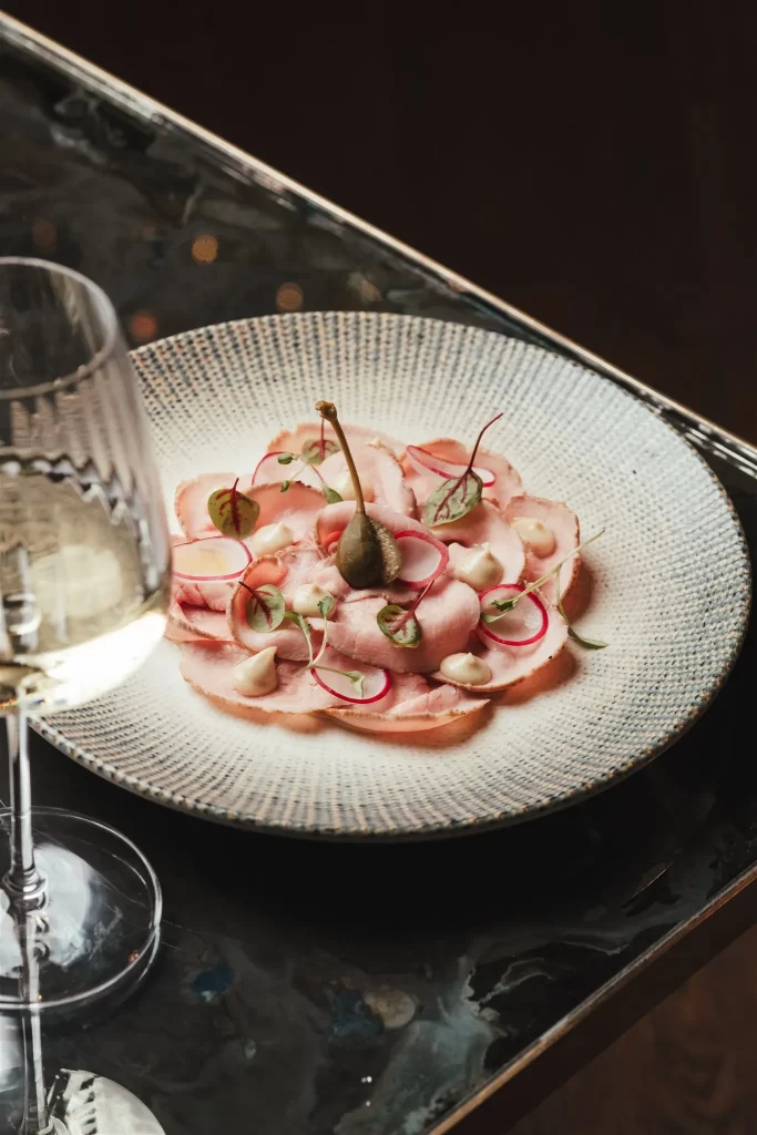 A plate of food with a glass of wine at a restaurant near Harrods.